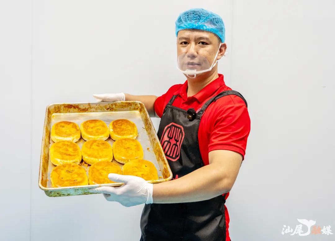 师傅端出金黄酥脆的刚出炉饼食，展现传统美食的匠心制作与诱人色泽。
